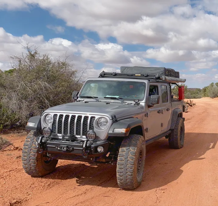 Off-road ready silver Jeep Gladiator with rooftop tent on a desert path. Perfect for an RV rental adventure.. Jeep Gladiator 2020