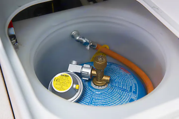 Essential RV rental equipment: a blue gas cylinder, regulator, and hose neatly stored.. Volkswagen California Ocean 2024