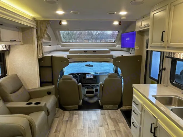 Spacious RV rental interior with cockpit, overhead bunk, cozy recliners, and a modern kitchen area.. Entegra Coach Odyssey 2022