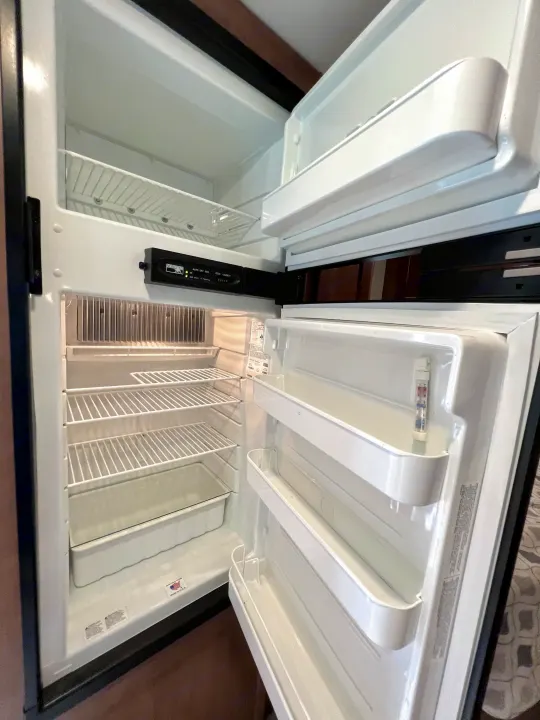 Empty, clean RV rental refrigerator interior with open doors, showing shelves, freezer, and door bins. Ready for use!. Winnebago Minnie Winnie 2020