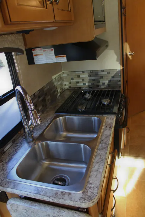 This RV rental kitchen features a modern double sink, gas stovetop, and stylish tiled backsplash.. Other Other 2017