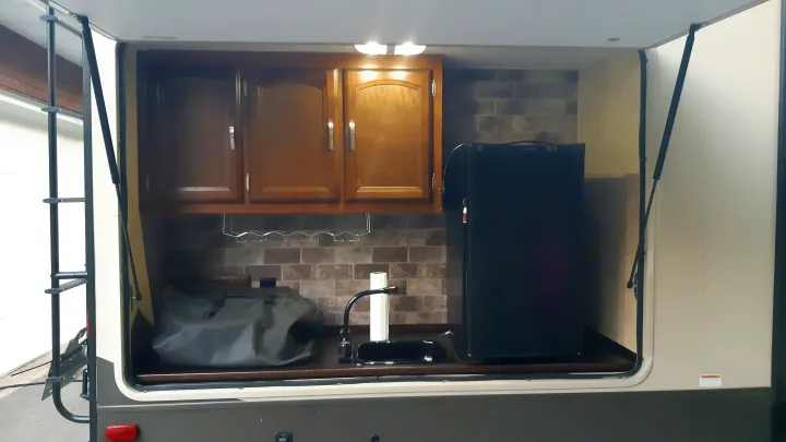 RV rental outdoor kitchen with sink, faucet, fridge, cabinets, and wine rack, offering convenient camping amenities.. Forest River Salem Hemisphere Lite 2016