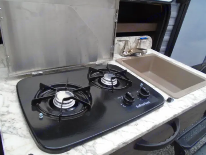 RV rental compact kitchen: features a two-burner Suburban stove with cover, a sink, and a modern faucet.. Jayco Jay Flight 2020