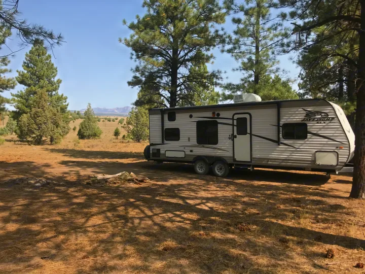 This RV rental is parked among pine trees, with mountains in the background, offering a serene outdoor escape.. Jayco Jay Flight SLX 2017