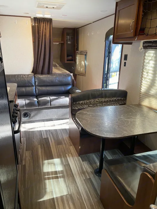 Interior of an RV rental showing the sofa, dinette, and kitchen area with wood-look flooring.. Jayco Jay Flight SLX 2017