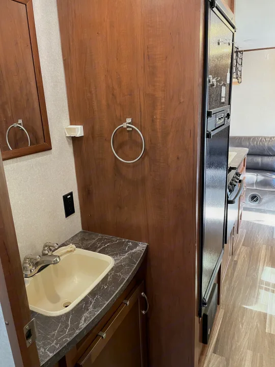RV rental interior: compact bathroom sink, full kitchen with refrigerator, and a glimpse of the living area.. Jayco Jay Flight SLX 2017