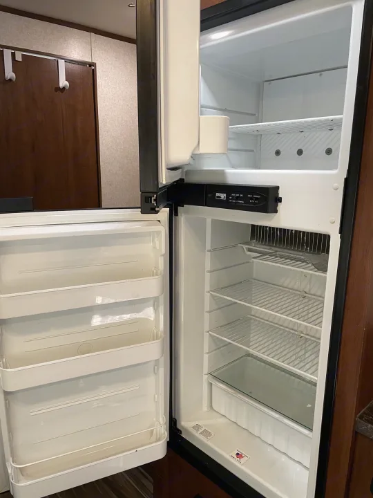 Empty, clean compact fridge inside an RV rental, doors open, revealing shelves and controls, ready for use.. Jayco Jay Flight SLX 2017