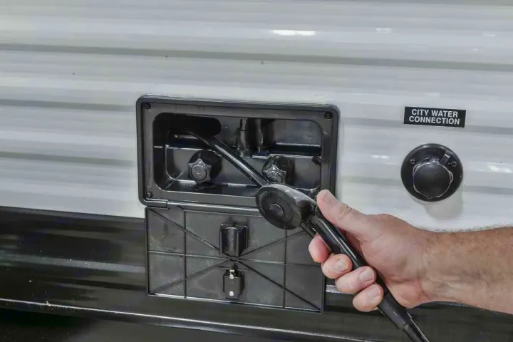 Hand operates RV rental's outdoor shower, with the city water connection nearby. Essential for camping water hookups.. Heartland RVs Prowler 2020