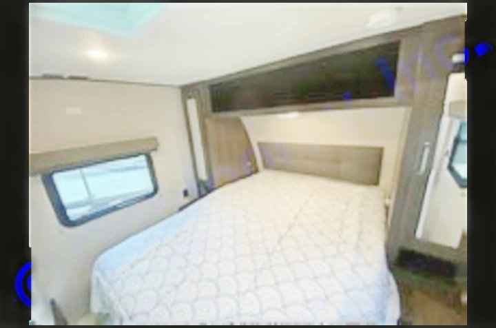 Cozy RV rental bedroom with a queen bed, overhead storage, and a large window, ideal for travel and camping.. Grand Design Transcend Xplor 2022