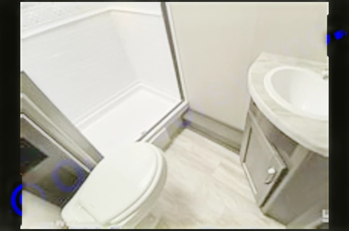 Inside an RV rental: a clean, compact bathroom with a glass-enclosed shower, toilet, and sink vanity.. Grand Design Transcend Xplor 2022