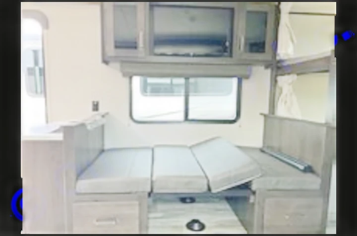 Inside an RV rental: a modern living space with a convertible dinette bed, TV, and bunk beds for family travel.. Grand Design Transcend Xplor 2022