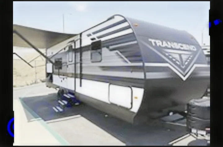 A black & white Transcend travel trailer, with its awning out, ready for RV rental adventures and outdoor travel.. Grand Design Transcend Xplor 2022