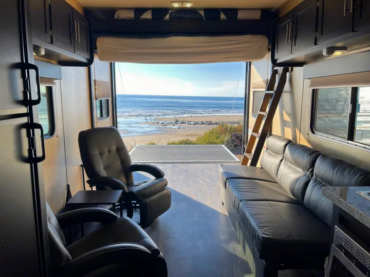 Spacious RV rental interior with ocean view from the open ramp, perfect for a relaxing glamping trip by the beach!. Dune Sport Toy Hauler 2017