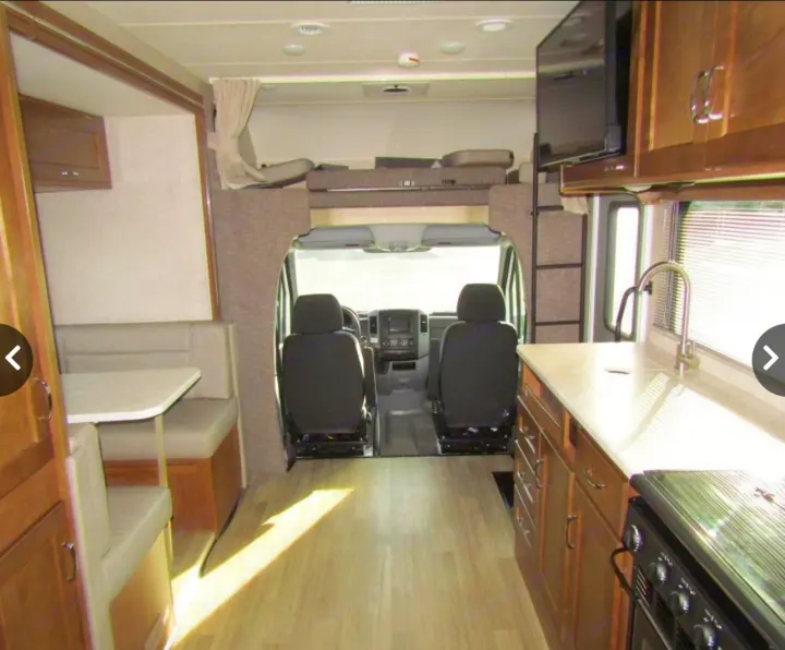 Bright rv rental interior with kitchen, dinette, and overhead bunk area, looking towards the cockpit.. Winnebago Vita 2019