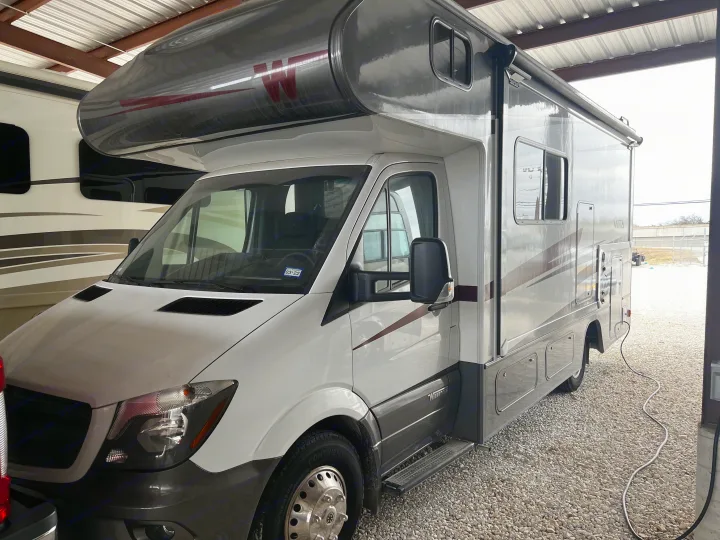 White and gray Winnebago Vita Class C RV rental, parked under a metal roof, is ready for your adventure.. Winnebago Vita 2019