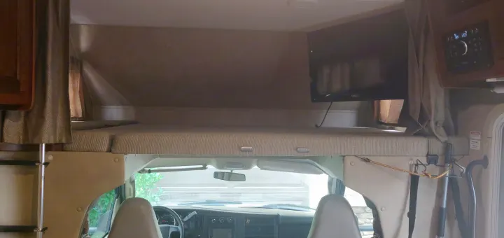 Experience comfort in this RV rental! View of the over-cab bunk bed, TV, and front vehicle cabin.. Forest River Forester 2017