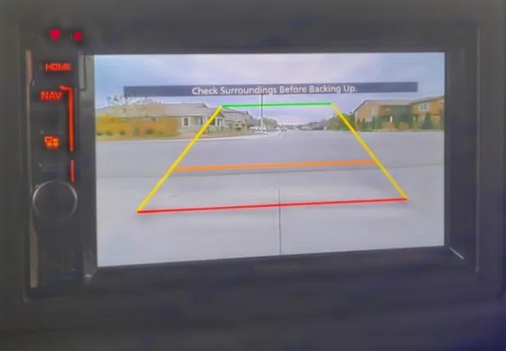 RV rental backup camera display: live street view with colored parking lines and a "Check Surroundings" safety warning.. Forest River Forester 2017