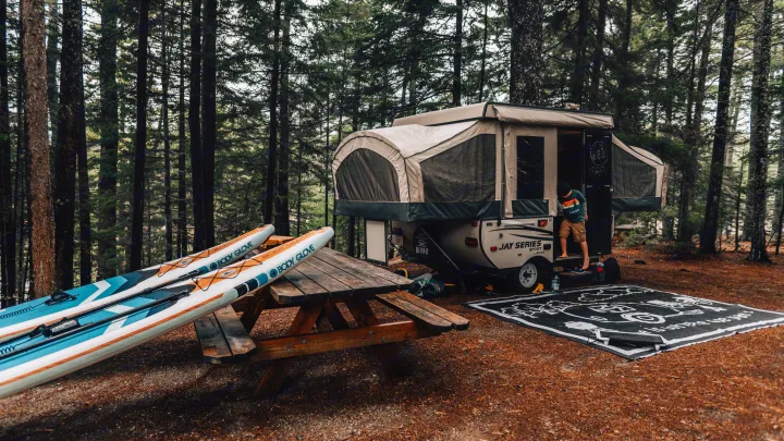 Enjoying nature with an RV rental: a campsite setup featuring a pop-up camper, paddleboards, and a picnic table.. Jayco Jay 2015