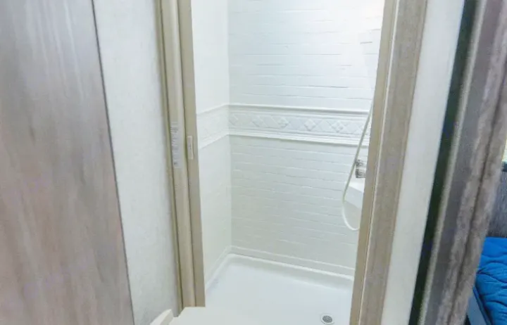 This rv rental features a compact shower with white brick-patterned walls, a shower pan, and a shower head.. Forester LE 2018