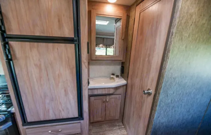 Compact RV rental interior featuring a bathroom vanity, sink, and part of the kitchen area with a refrigerator.. Forester LE 2018