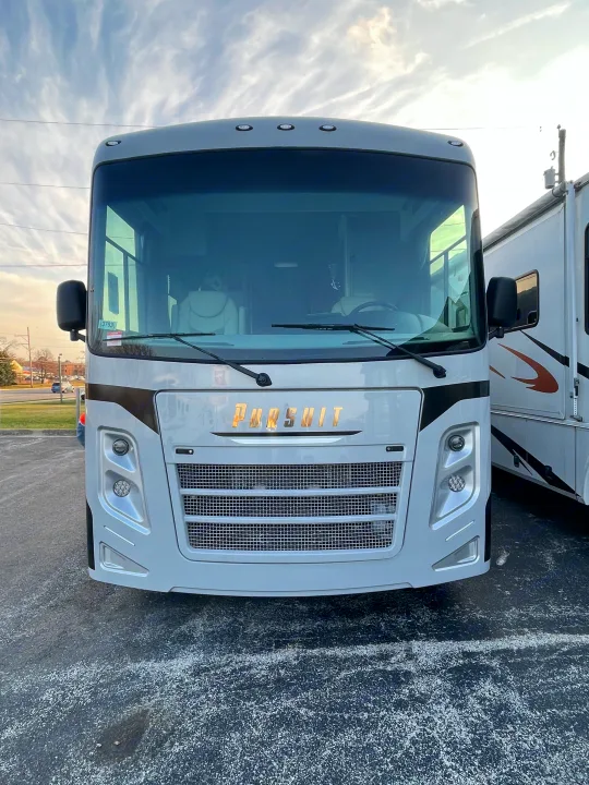 Front of a light-colored Pursuit motorhome, potentially an RV rental, with a large windshield and grille, parked on asphalt.. Forest River Coachmen Pursuit 2022