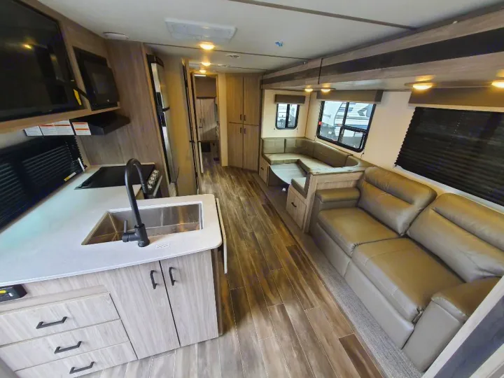 Explore this spacious RV rental interior! Features a full kitchen, comfy sofa, and dining area. Perfect for your next adventure.. Keystone RV Passport SL 2022