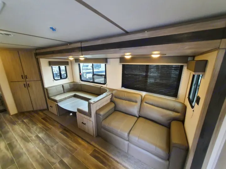 Spacious RV rental interior with dinette seating, sofa, and wood flooring.. Keystone RV Passport SL 2022