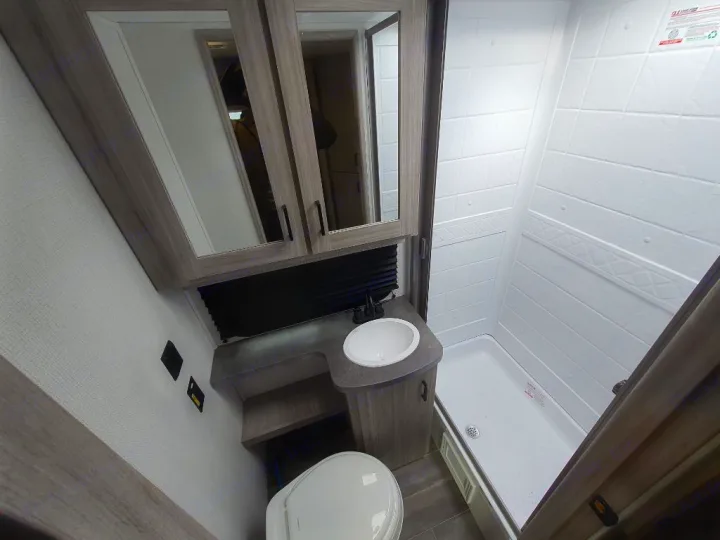 This RV rental features a clean, compact bathroom with a toilet, sink, and full shower. Ideal for camper travel.. Keystone RV Passport SL 2022