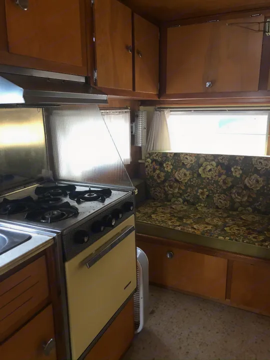 Step inside this cozy rv rental! Features include a vintage kitchen with stove, sink, wood cabinets, and floral upholstered dinette.. Holiday Rambler Traveler 1964