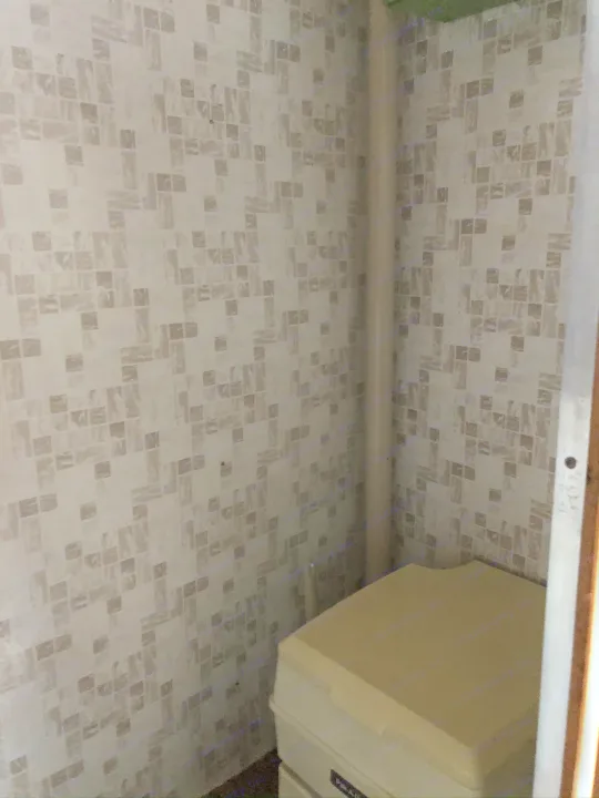 Inside an **rv rental**: a compact portable toilet and patterned walls. Essential facilities for travel.. Holiday Rambler Traveler 1964