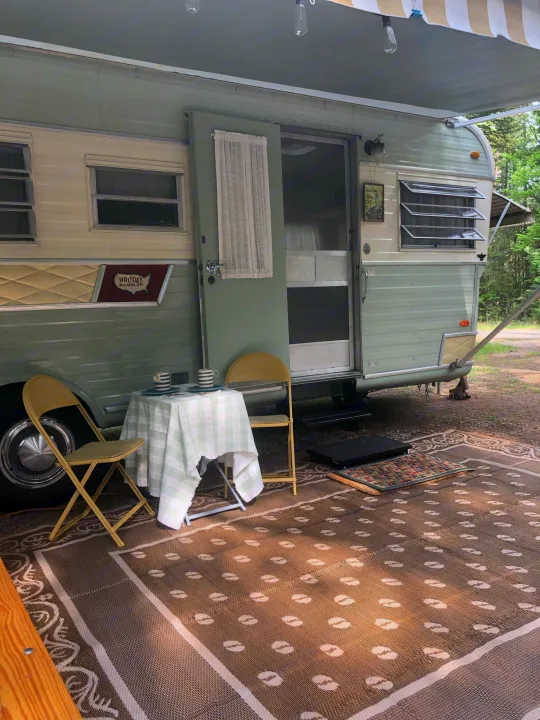 Cozy vintage RV rental set up with outdoor rug, table, & chairs. Perfect for camping adventures!. Holiday Rambler Vacationer 1969