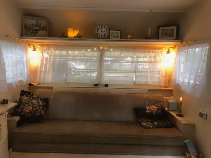 Cozy RV rental interior with inviting seating, warm lighting, and decorative shelf.. Holiday Rambler Vacationer 1969