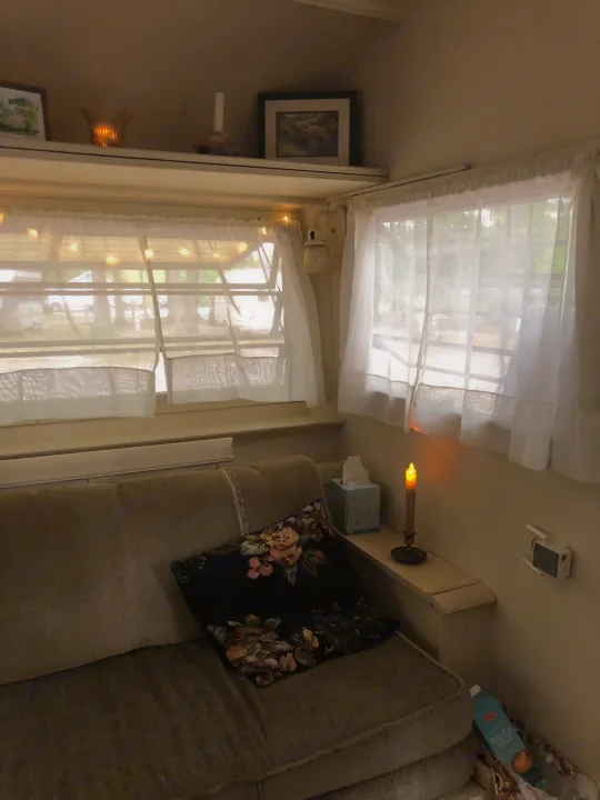 Inside a comfy RV rental, featuring a sofa, sheer curtains, and ambient lighting for a relaxing stay.. Holiday Rambler Vacationer 1969