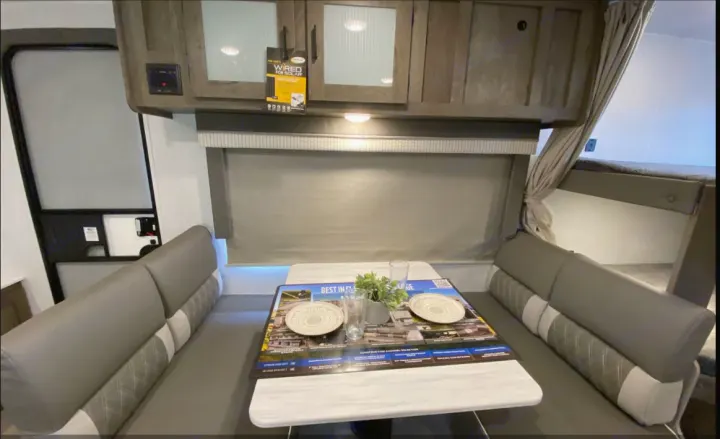 RV rental dinette with table, benches, & overhead cabinets. Bunk beds visible to the right.. Forest River Salem Cruise Lite 2022