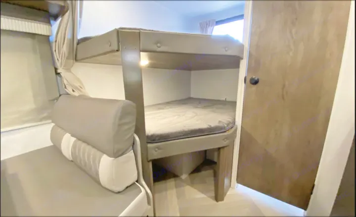 Cozy bunk beds in this RV rental's interior, featuring a lower mattress, an adjacent dinette seat, and a privacy door.. Forest River Salem Cruise Lite 2022
