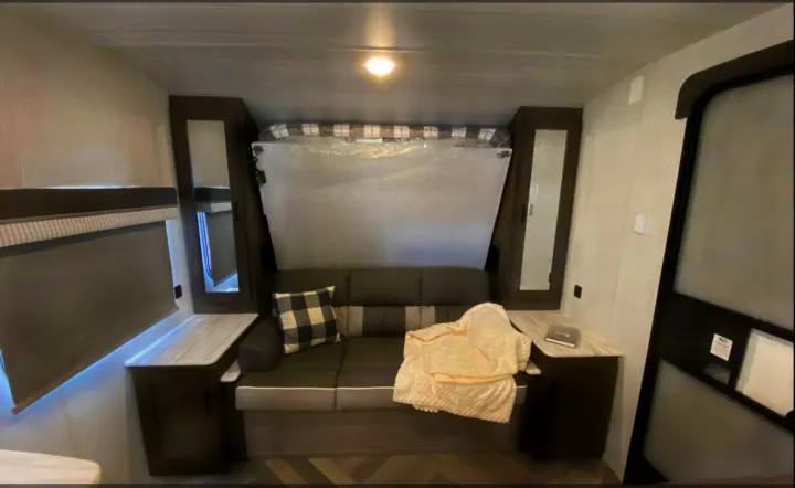 Cozy & functional RV rental: features a convertible sofa with plaid pillow & blanket, tucked murphy bed, and storage units.. Forest River Salem Cruise Lite 2022