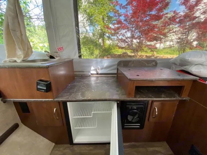 RV rental: Compact pop-up camper kitchen featuring a sink, open refrigerator, and countertop, ready for camping trips.. Jayco Sport 2016