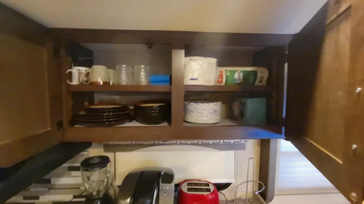 Organized RV rental kitchen cabinet: dishes, paper towels, & counter appliances. Your adventure's fully stocked!. Thor A.C.E. 2018
