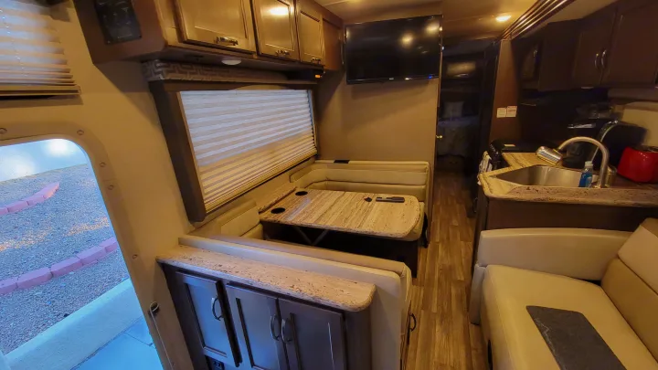 Explore this modern RV rental's spacious interior, featuring a full dinette, kitchen, living area with TV, and bedroom access.. Thor A.C.E. 2018