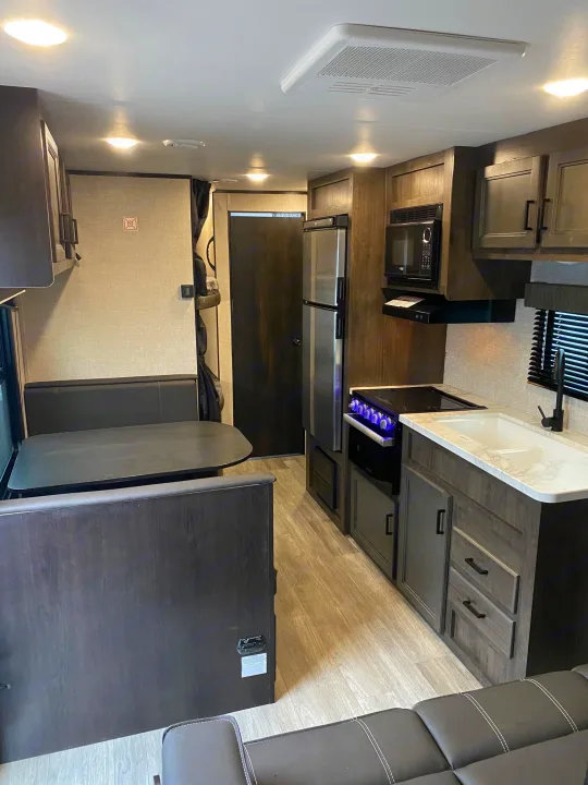 Modern RV rental interior featuring a well-equipped kitchen, comfortable dinette, and living area with dark cabinetry.. Jayco Jay Flight SLX8 264BH 2022