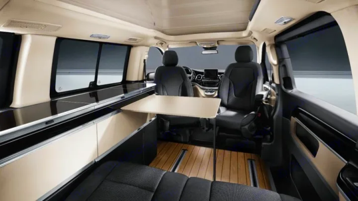 Experience comfort in this RV rental camper van interior. Features a versatile table, rear seating, storage, and wood flooring.. Mercedes Marco Polo 2022