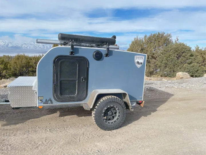 Grey off-road teardrop camper ready for your RV rental mountain adventure. Features diamond plate storage & roof rack.. Sherpa trailers Big foot 2022