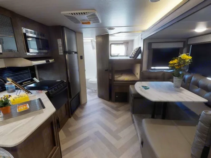 Explore this compact RV rental interior featuring a kitchen, cozy dining booth, and bunk beds for extra sleeping.. Forest River Salem Cruise Lite 2020