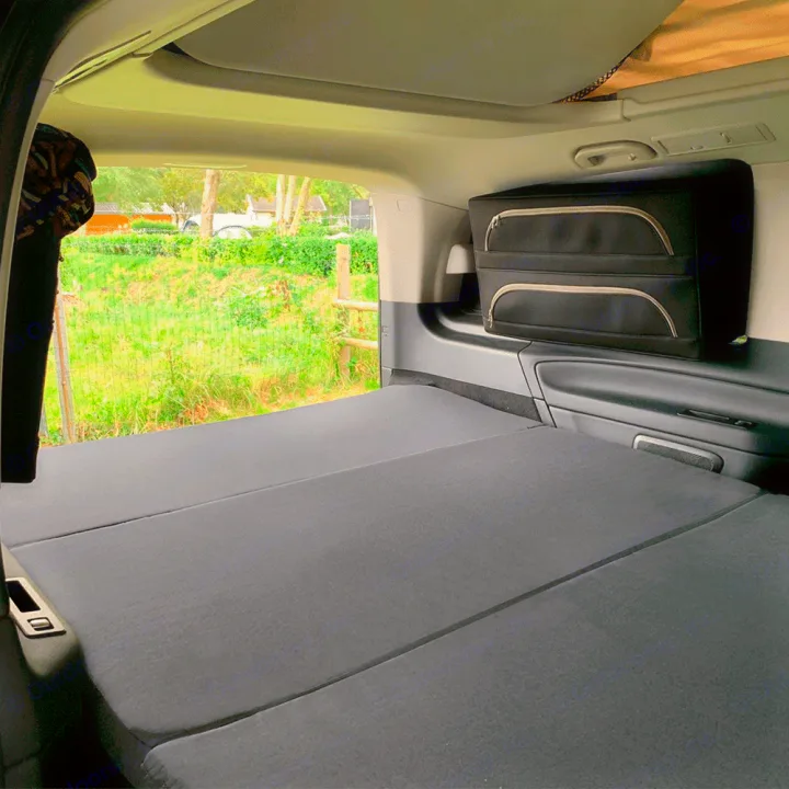 RV rental: Camper van interior with a large, dark gray fold-out bed and side storage, overlooking a green outdoor scene.. Mercedes Marco Polo 2022