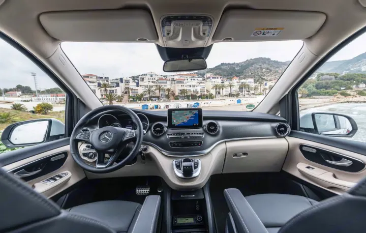 Driver's view inside a Mercedes-Benz van, showcasing a sleek dashboard with navigation screen and a scenic coastal town. Ideal for an RV rental.. Mercedes Marco Polo 2022