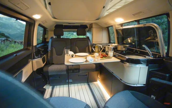 Cozy camper van interior with kitchen, dining area set for two. Ideal for your next RV rental adventure in nature.. Mercedes Marco Polo 2022