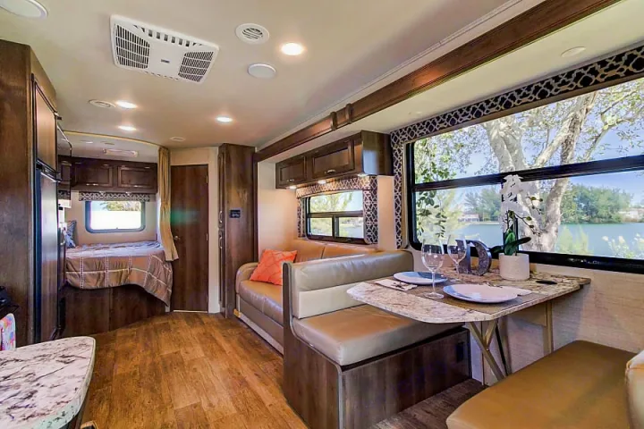 Spacious RV rental interior featuring a cozy dining area, comfortable sofa, and a bedroom, perfect for a relaxing getaway.. Jayco Redhawk 2018