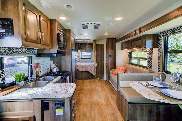 Inside this RV rental: a modern kitchen, dining booth, and bedroom. Experience comfortable mobile living.. Jayco Redhawk 2018