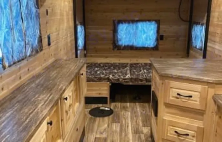 Explore this ice fishing house RV rental interior: wood-paneled walls, counters, and bed/seating. Perfect for mobile comfort on the ice.. Glacier Ice House Glacier Ice House Trailer 2019