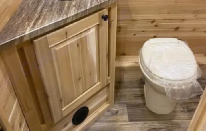 This RV rental bathroom features a clean toilet with protective plastic wrap and a rustic wooden vanity.. Glacier Ice House Glacier Ice House Trailer 2019